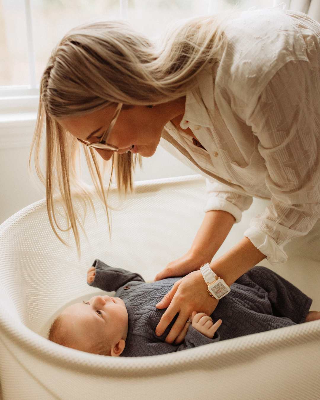 Mother or doula caring for her newborn baby in a crib with postpartum support at home