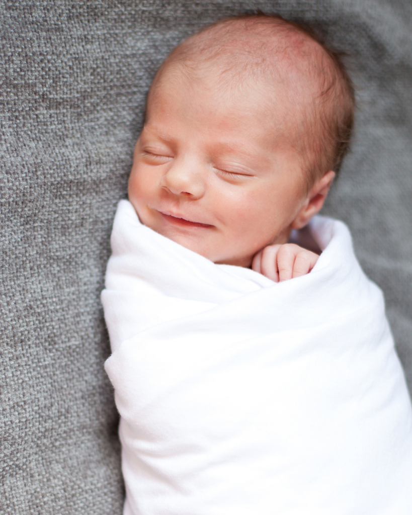 Happy swaddled newborn baby sleeping peacefully during overnight doula support